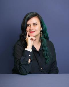 Headshot of Bilgen Turkay blue gray background.