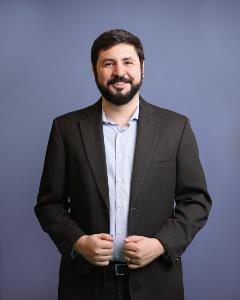 Headshot of Eduardo Martinez standing gray background
