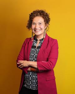 Headshot of Felicia Zamora standing orange yellow background