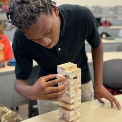 Close-up student moving Jenga blocks in Project Management activity